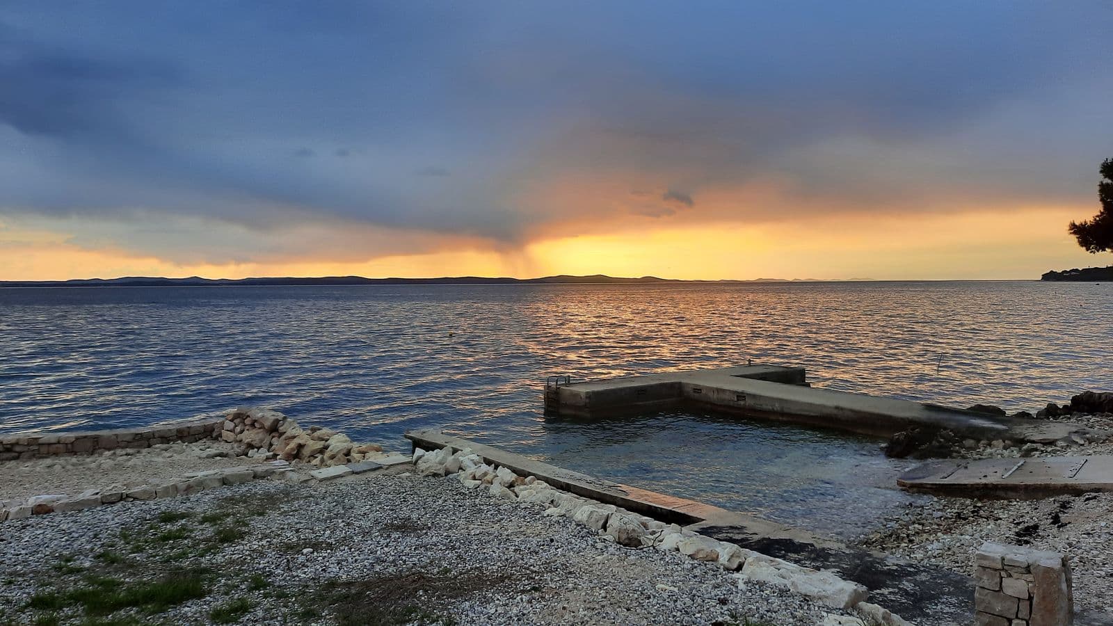 Pebble beach with a small jetty at sunset
